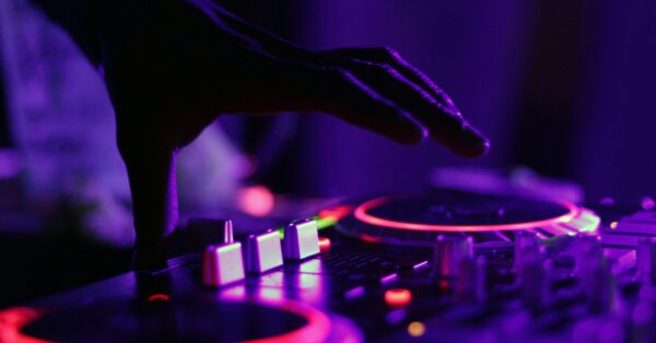 selective focus silhouette photography of man playing red-lighted DJ terminal